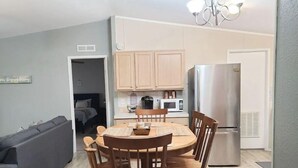 Un espace de vie compact comprenant un coin repas, une kitchenette et un canapé gris.