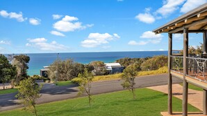 Une propriété située en bord de mer, offrant une vue sur l’océan, avec une allée pavée et un espace extérieur couvert.