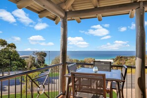 A covered outdoor seating area with a table and chairs, overlooking a scenic ocean view. - Great views in quiet cul de sac, Point Lookout (Point Lookout)