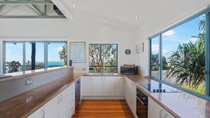 Une cuisine moderne dotée de grandes fenêtres, de plans de travail en bois et offrant une vue sur la mer.