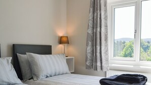 A bedroom with a bed, a nightstand with a lamp, and a window with curtains. - Enviable location within the golf course. (Skipton)