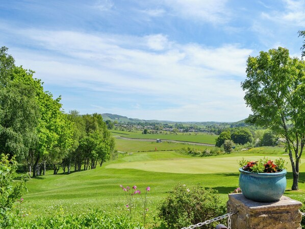 A lush green landscape with a golf course, trees, and a stone structure with a flower pot. - Enviable location within the golf course. (Skipton)