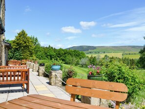 A patio with wooden benches and stone pillars, overlooking a lush valley with rolling hills and a clear sky. - Enviable location within the golf course. (Skipton)