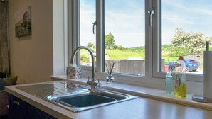 A kitchen with a sink, window, and view of a parking lot. - Enviable location within the golf course. (Skipton)