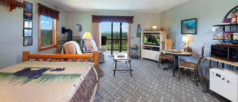 A hotel room with a bed, a desk, a chair, a television, and a view of the outdoors.