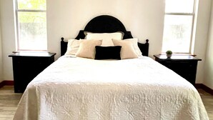 Ein Schlafzimmer mit einem Bett, zwei Nachttischen und zwei Fenstern.