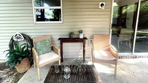 Eine Veranda mit Korbstühlen, einem Holztisch und einem Blumentopf.