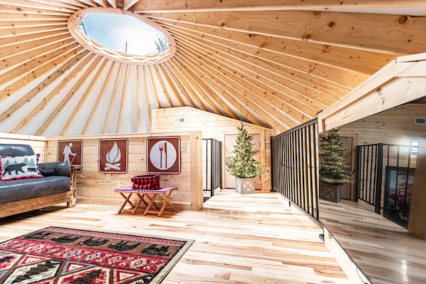 A spacious room with a wooden ceiling, a sofa, a small table, and a Christmas tree.