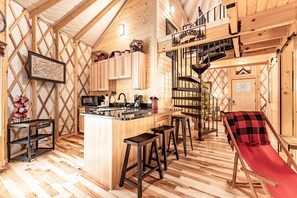 A cozy cabin interior with a kitchen, dining area, and a red slide.