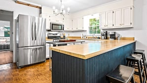 A modern kitchen with a large island, stainless steel appliances, and white cabinetry.