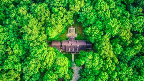 An aerial view of a house surrounded by dense green forest.
