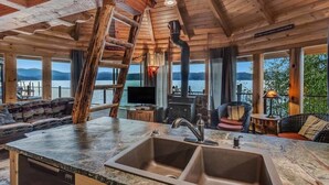Interior rústico de una cabaña con encimera de piedra, un lavabo, un televisor y una chimenea.