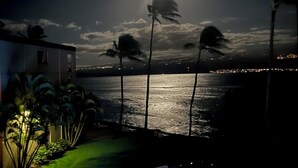 A nighttime view of a pool area with a clear view of the ocean and a starry sky. - Relaxing Oceanfront! (Wailuku)