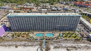 Un grande hotel con diversi piani, una zona piscina centrale e una spiaggia in primo piano.