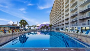 Una piscina con lettini, un edificio di un hotel e palme.