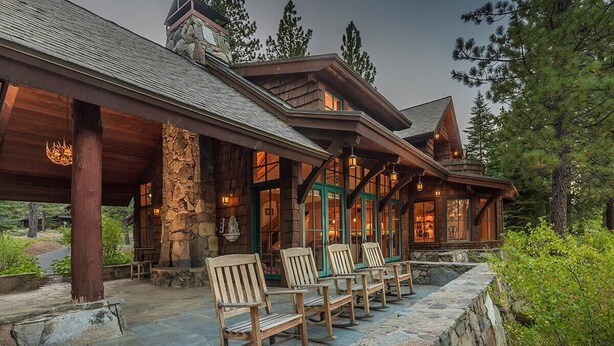A rustic lodge with a stone facade, wooden rocking chairs, and a stone pathway leading to the entrance. - MONTHLY LEASE - Luxury 4 BR 4 BA Truckee Available March 2022 (Truckee)