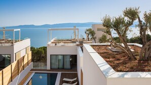 A modern pool area with a view of the sea, wooden deck, and lounge chairs. - Wind Rose Wellness Villa Maestral (Marušici)