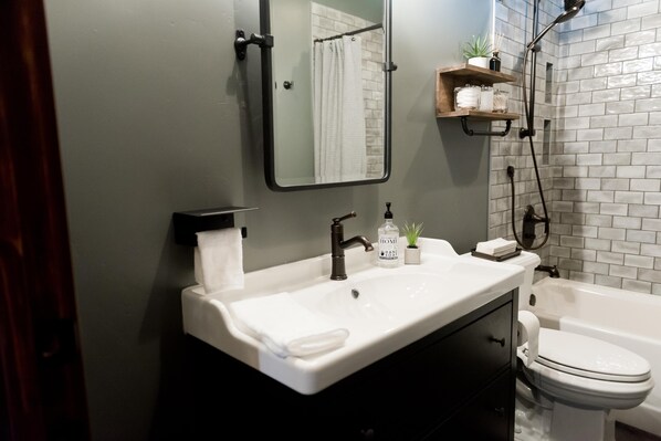 Un baño con un lavamanos blanco, un espejo, un inodoro y una zona de ducha.