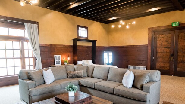 A large L-shaped sectional sofa with multiple pillows, a wooden coffee table, and a framed picture on a wall. - Depot Flat - Kitchenette, 2 Queen Murphy Beds, Large Sitting Area (Logan)