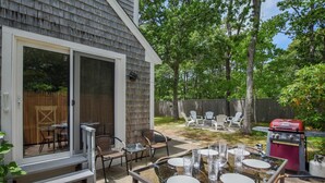 A patio with a glass table, wicker chairs, and a barbecue grill. - Great Home with Game Space, 0.8 miles from Cooks Brook Beach! (Eastham)