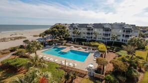 A hotel with a large pool, beach view, and multiple balconies.