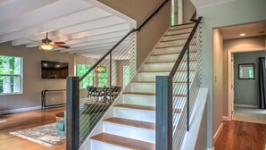 A staircase with wooden steps and metal railings, leading to a dining area with a table and chairs.