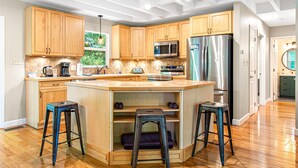 A modern kitchen with wooden cabinets, stainless steel appliances, and a central island with stools.