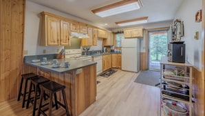 Una cocina con armarios de madera, una isla central con taburetes, un refrigerador y un horno empotrado.