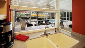 Una cocina con un lavamanos, una cafetera y vistas a una piscina.