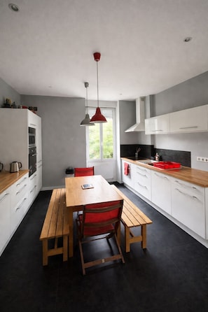 Una cocina moderna con armarios blancos, una mesa de madera y sillas rojas.