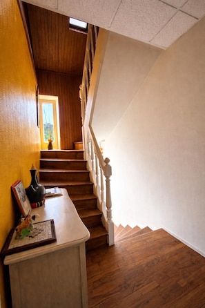 Una escalera de madera con barandillas blancas que lleva a un rellano.