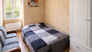 A bedroom with a bed, a chair, a wardrobe, and a window. - Namaste Duplex Gare Nantes  (Nantes)