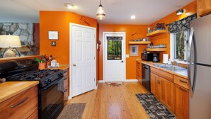 A kitchen with wooden cabinets, a stainless steel refrigerator, a stove, and a microwave. - 2 Miles to Good Harbor Beach, Pet Friendly (Cedar)