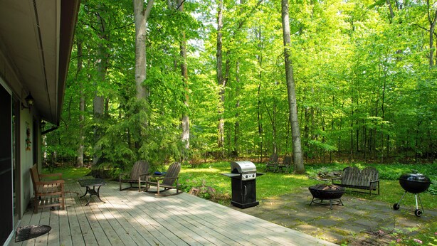 A wooden deck with outdoor furniture, a grill, and a fire pit. - 2 Miles to Good Harbor Beach, Pet Friendly (Cedar)
