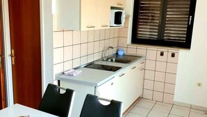 A compact kitchen with white cabinets, a microwave, and a window with blinds. - Lovely 1-bed Apartment With sea View in Srima (Vodice)