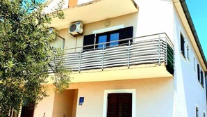 A two-story building with a balcony, a satellite dish, and a small garden area. - Lovely 1-bed Apartment With sea View in Srima (Vodice)