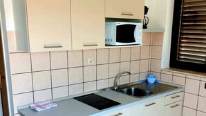 A compact kitchen with a microwave, sink, and a small refrigerator. - Lovely 1-bed Apartment With sea View in Srima (Vodice)