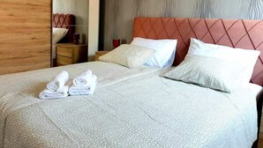 A hotel room with a bed, two pillows, a folded towel, a wooden wardrobe, and a mirror. - Lovely 1-bed Apartment With sea View in Srima (Vodice)