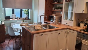 Een keuken met een houten kookeiland, witte kasten, een inbouwoven en een raam met uitzicht op de omgeving.
