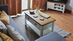 Een woonkamer met een bank, een salontafel, een televisie op een meubel en gordijnen.