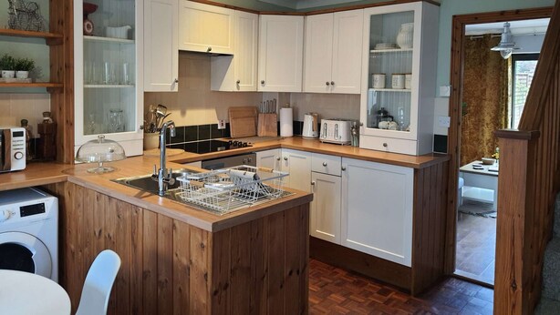 Een compacte keuken met houten kastjes, een inbouwvaatwasser en een klein eiland met een spoelbak.