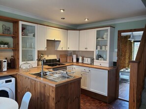 Una cocina compacta con armarios de madera, lavavajillas integrado y una pequeña isla con fregadero.