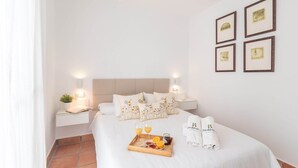 Ein Hotelzimmer mit Bett, Nachttischen, einem Tablett mit Frühstücksangeboten und gerahmten Bildern an der Wand.