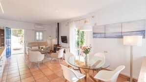 Ein modernes Wohnzimmer mit einem Glastisch, weißen Stühlen, einer Couch und einem Fernseher.