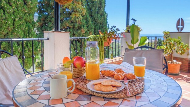 Ein Frühstückstisch auf einer Terrasse mit Meerblick, komplett mit Stühlen.