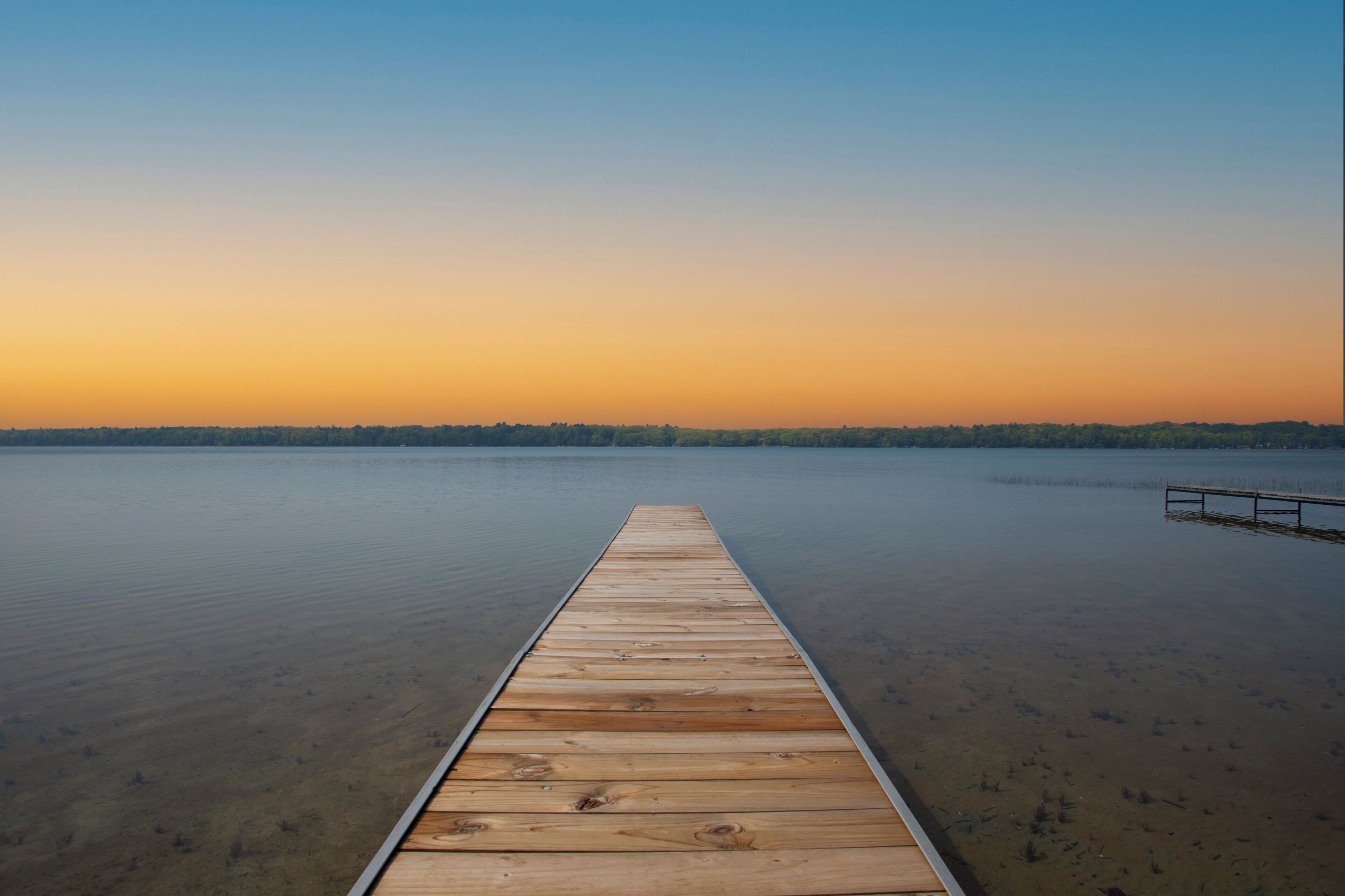 A wooden pier extending into calm water with a clear horizon.