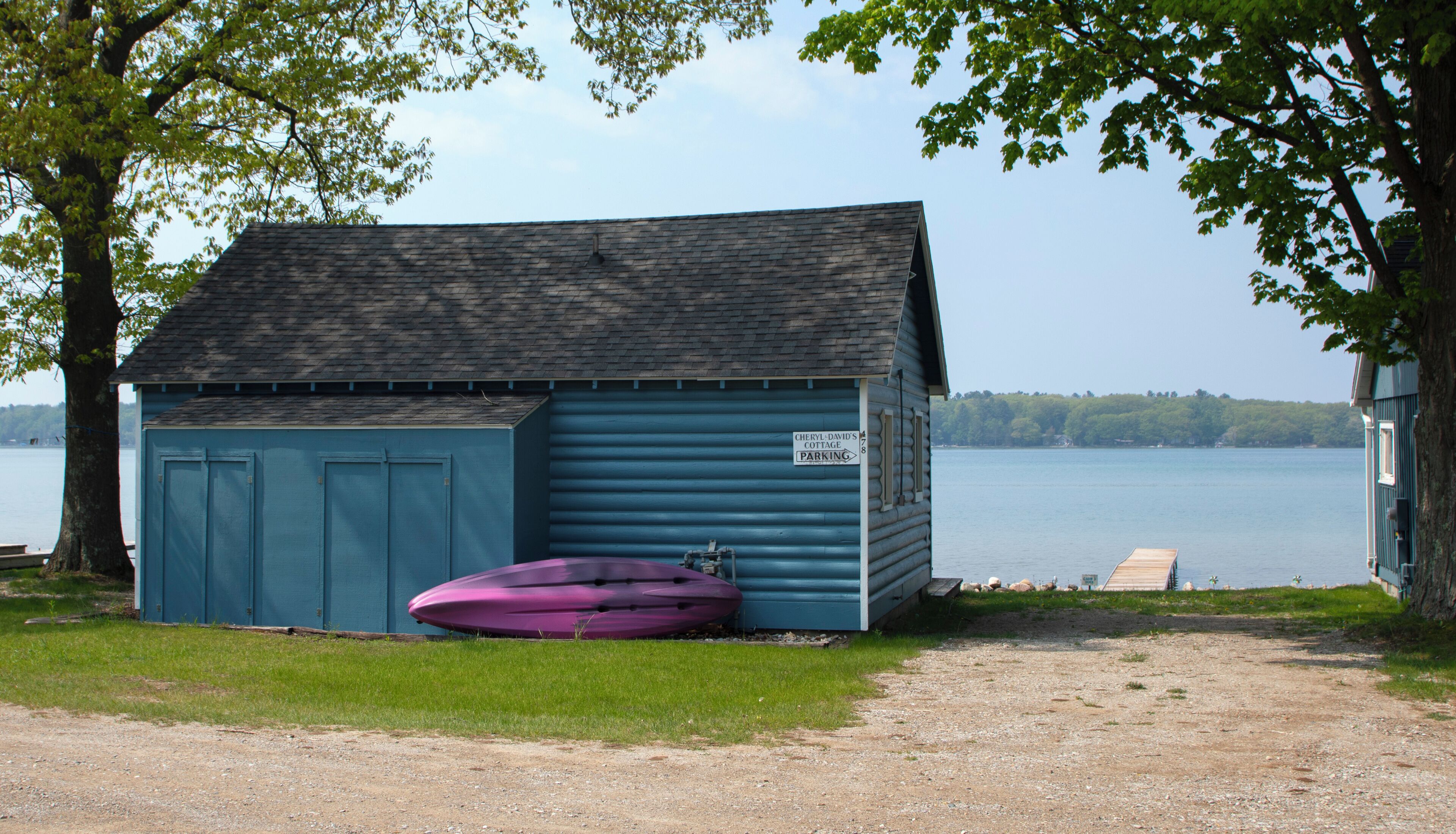 Un cobertizo azul pequeño con un letrero que indica 'Cheryl-David's Cottage Parking'.