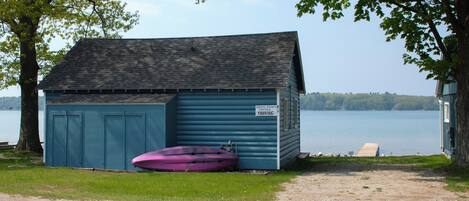 Un cobertizo azul pequeño con un letrero que indica 'Cheryl-David's Cottage Parking'.