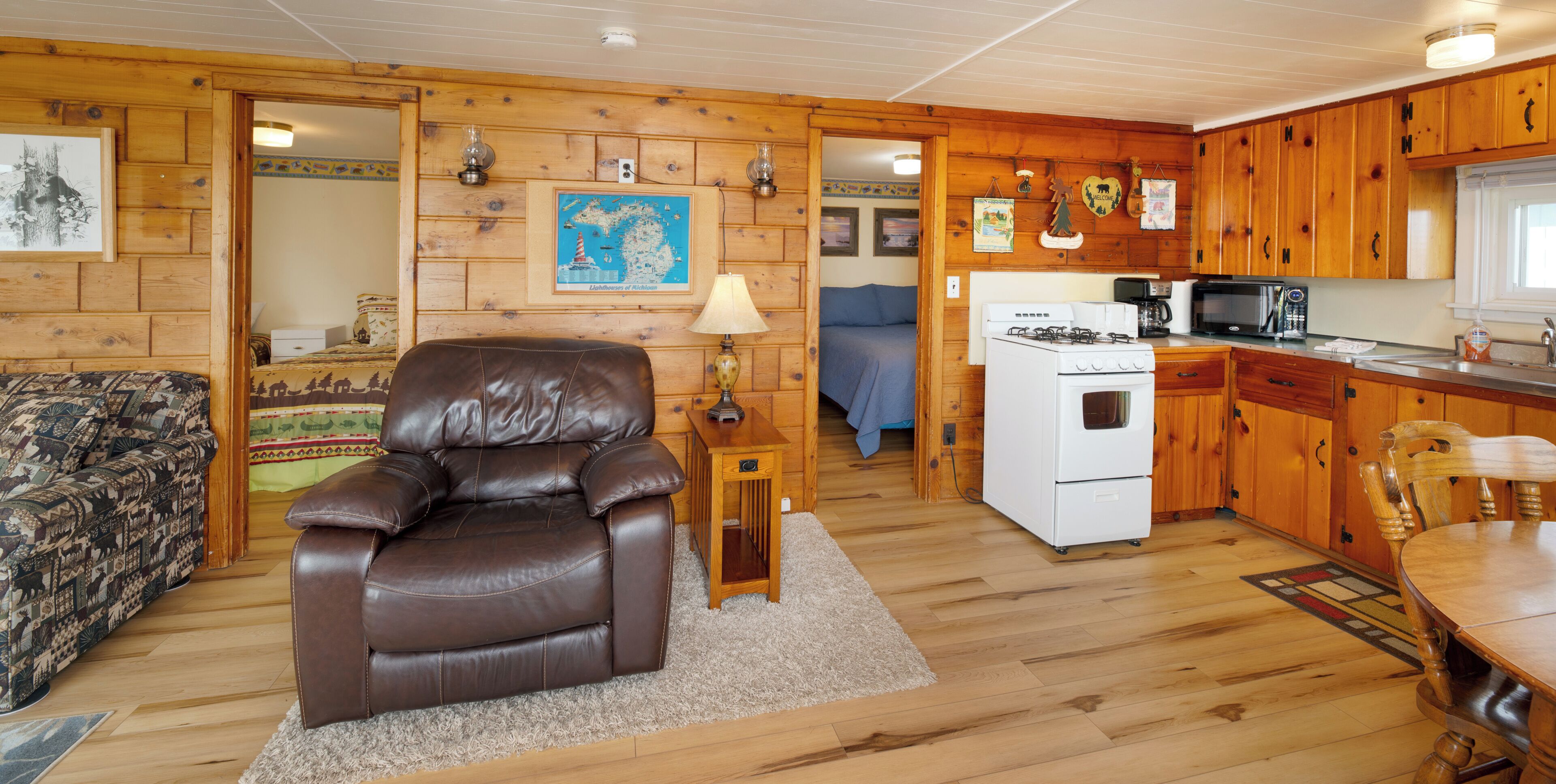 A cabin interior with a leather recliner, kitchenette, wooden walls, and a map on the wall.