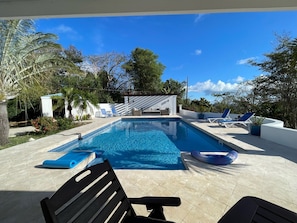 Relax by the serene pool surrounded by lush greenery and lounge chairs.